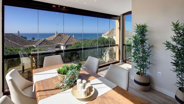 A modern dining area with a large glass window overlooking a coastal view. - AMAZING DUPLEX NEXT TO THE BEACH IN MARBELLA (Marbella)