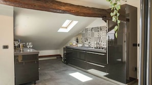 Eine moderne Küche mit Oberlichter, dunklen Schränken und einem Edelstahl-Kühlschrank.