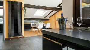 Eine moderne Küche mit schwarzem Arbeitsplatz, ein Essbereich mit weißen Stühlen und ein Oberlicht über dem Esstisch.