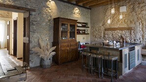 A rustic kitchen with stone walls, wooden cabinetry, and a bar area with stools. - CA’ DEL BUSO   (VERONA)