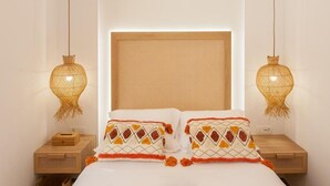 Un dormitorio ordenado con una cama grande, dos mesitas de noche y un cabecero con panel de respaldo tejido.