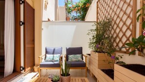 Un pequeño patio con dos sillas, una mesa y plantas en macetas.