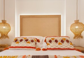 Una cama con dos almohadones decorativos, un cabecero tejido y dos lámparas colgantes.