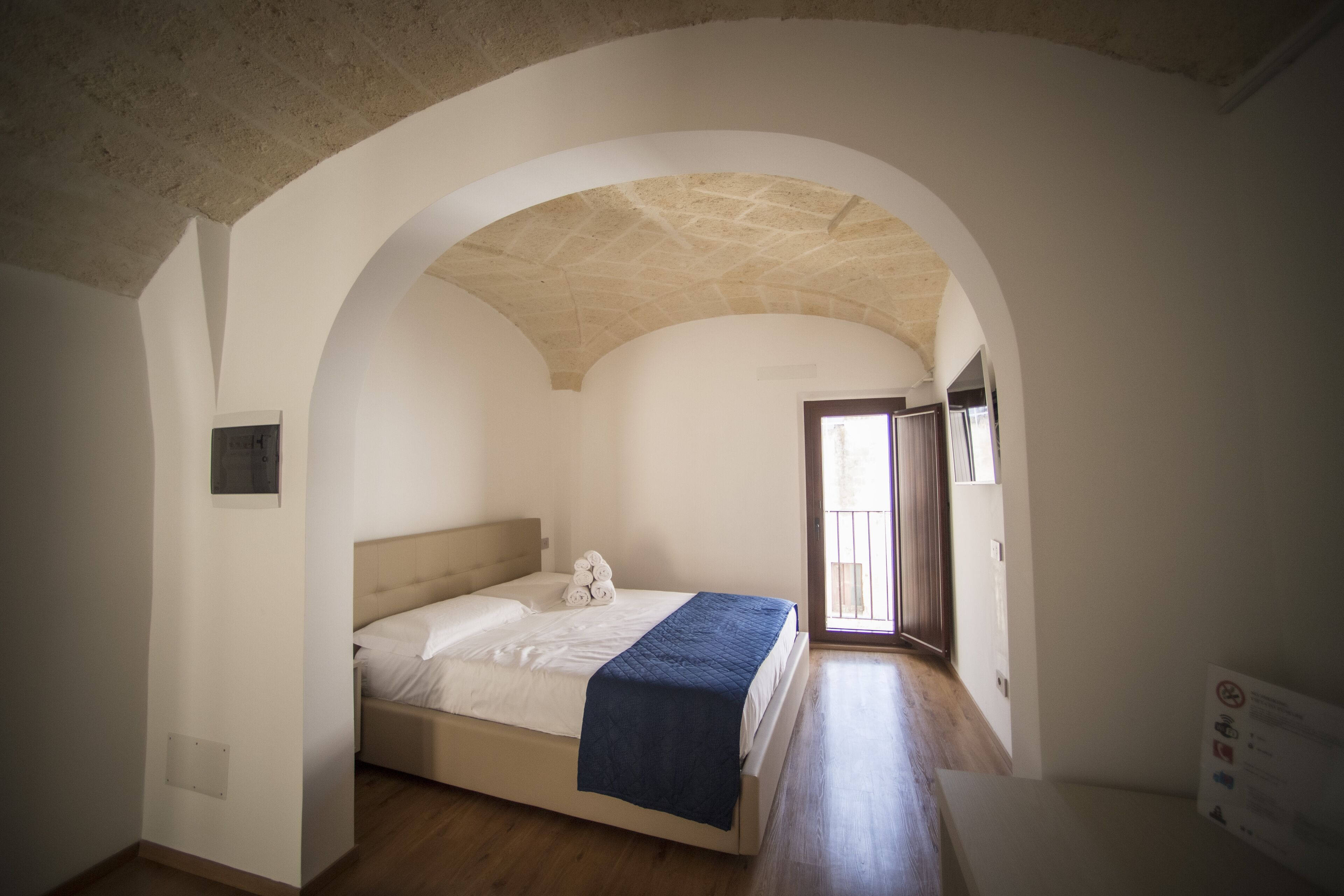 A bedroom with a bed, a blue blanket, and a towel.