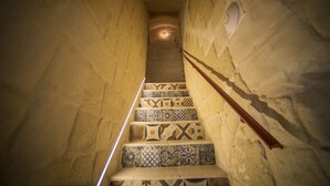 A staircase with patterned tiles leading to a ceiling light. - La Dimora del Principe (Grottaglie)