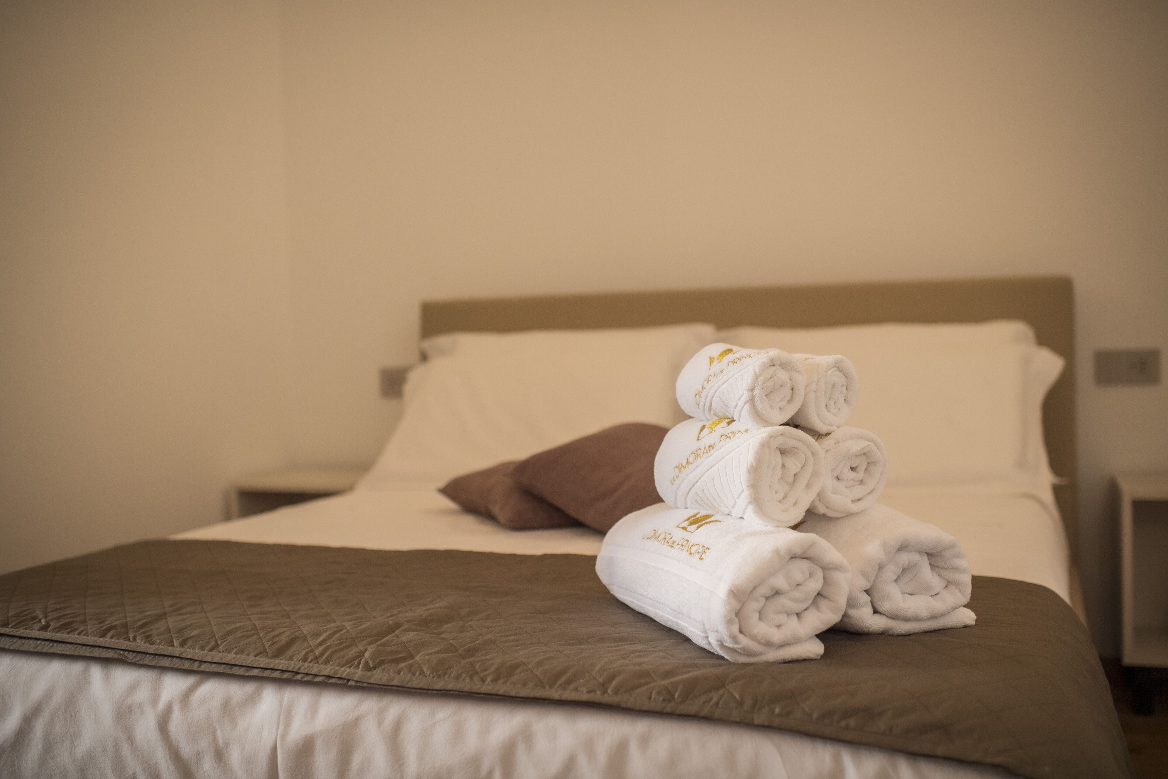 A neatly made bed with a brown quilted bedspread and a brown pillow.