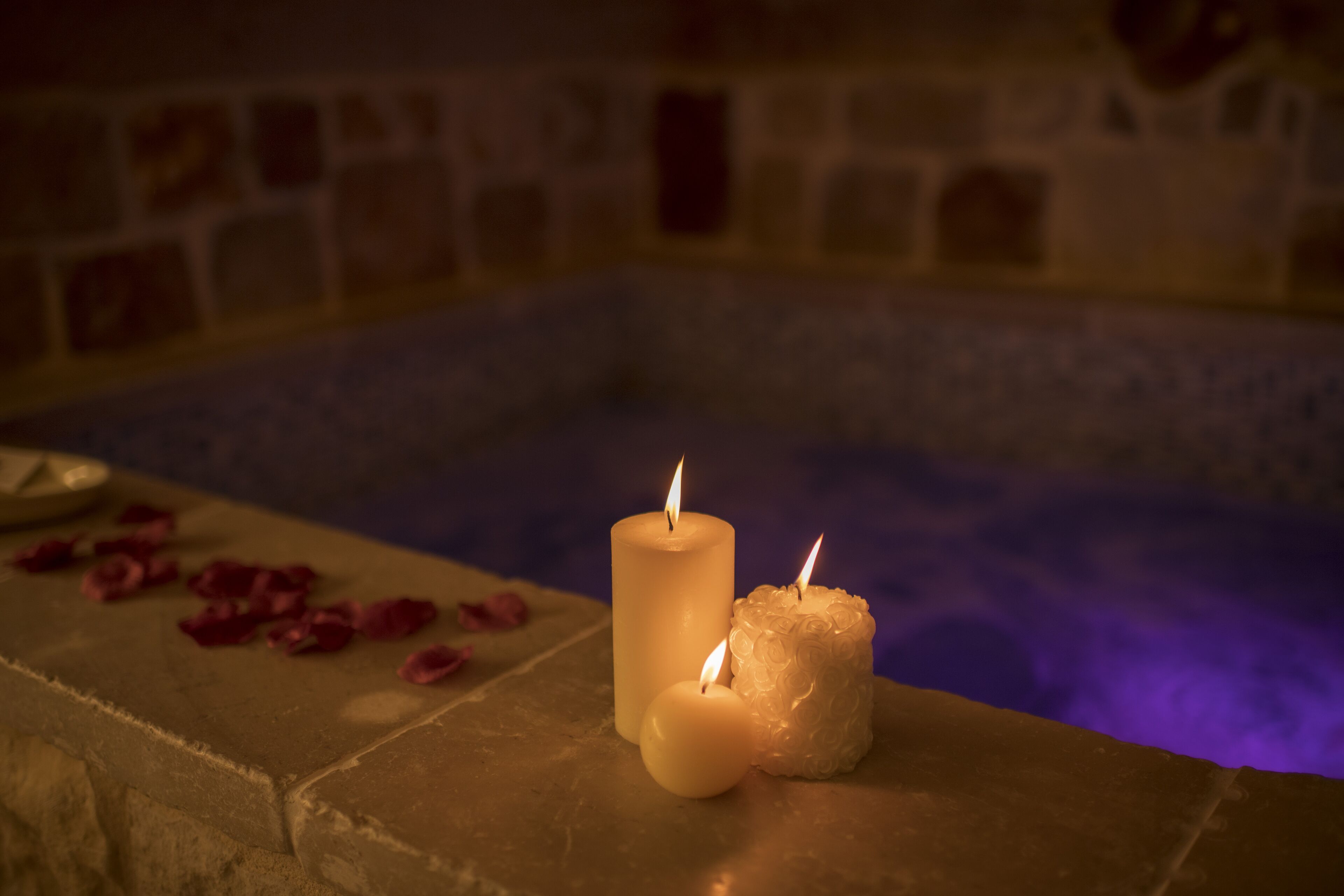 Eine Steinbadewanne mit Kerzen und Rosenblüten.
