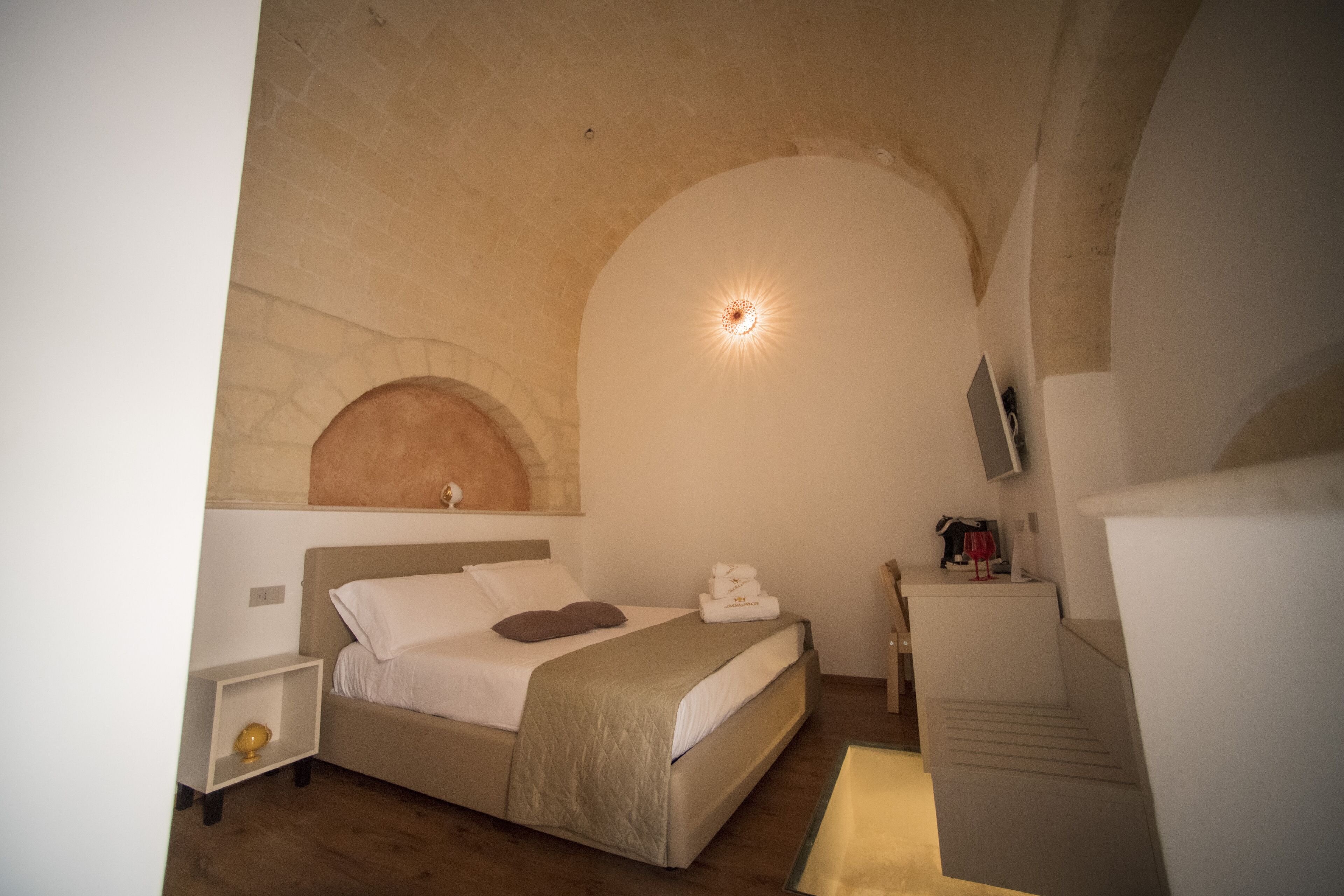 Un dormitorio con cama, mesita de noche, televisor y una escalera.