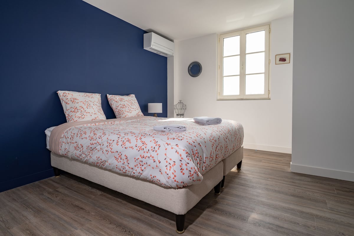 A bedroom with a bed, a window, and a wall-mounted air conditioner.