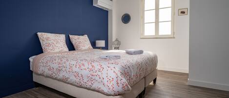 A bedroom with a bed, a window, and a wall-mounted air conditioner.