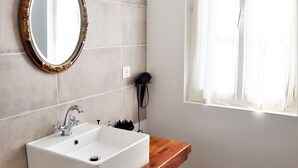 Un baño con tocador de madera, lavamanos blanco y espejo con marco decorado.