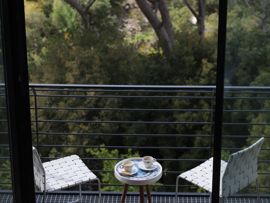 Un balcon avec deux chaises et une petite table sur laquelle se trouvent une tasse et une soucoupe.