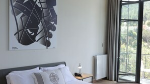 A modern hotel room with a large bed, a nightstand, a window with curtains, and a city view. - The Silk Valley Resort (Aarbaniye)