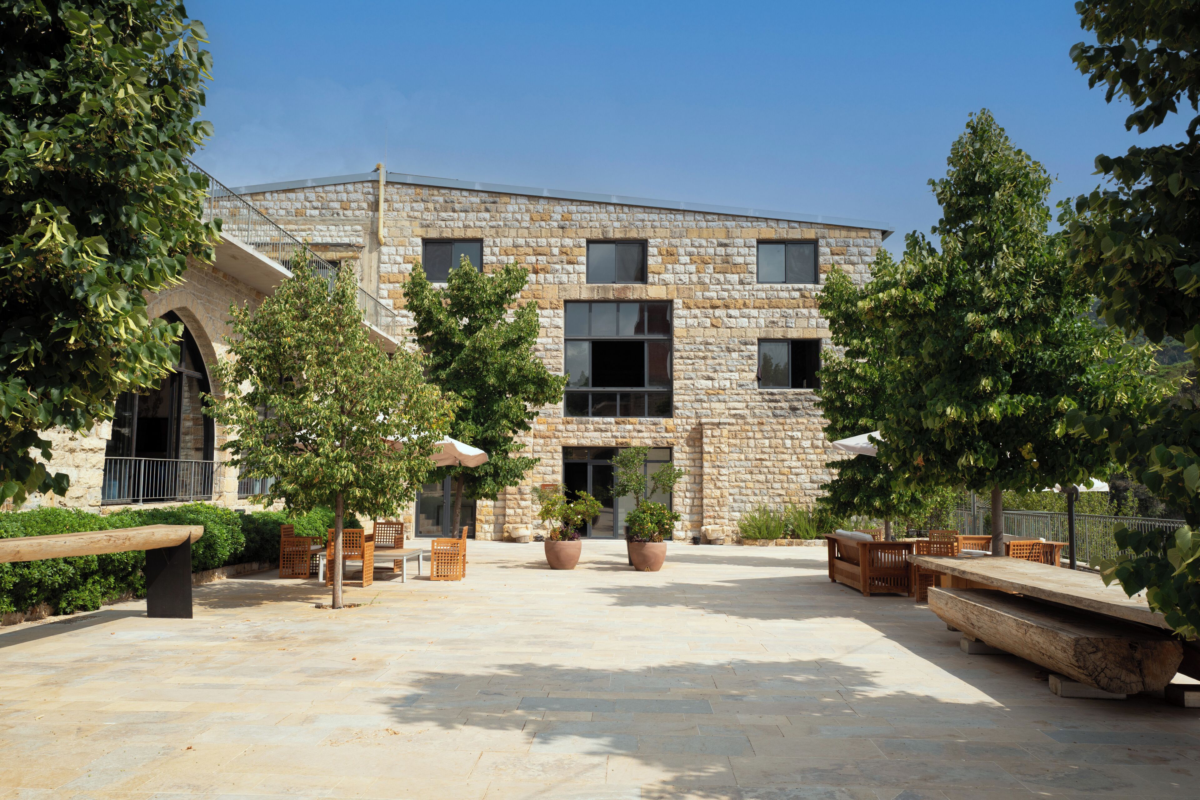 A courtyard with stone buildings, outdoor seating, and potted plants.