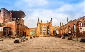 An open courtyard with stone paving, benches, and Gothic-style architecture. - Contractorscleancharming 2-bed House in Coventry (Coventry)