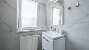 Un baño con lavamanos blanco, espejo y radiador.