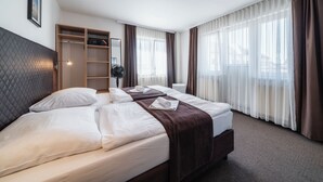 A hotel room with two beds, a wardrobe, a mirror, and a window with curtains. - Penzion Homér Slaný (Slany)