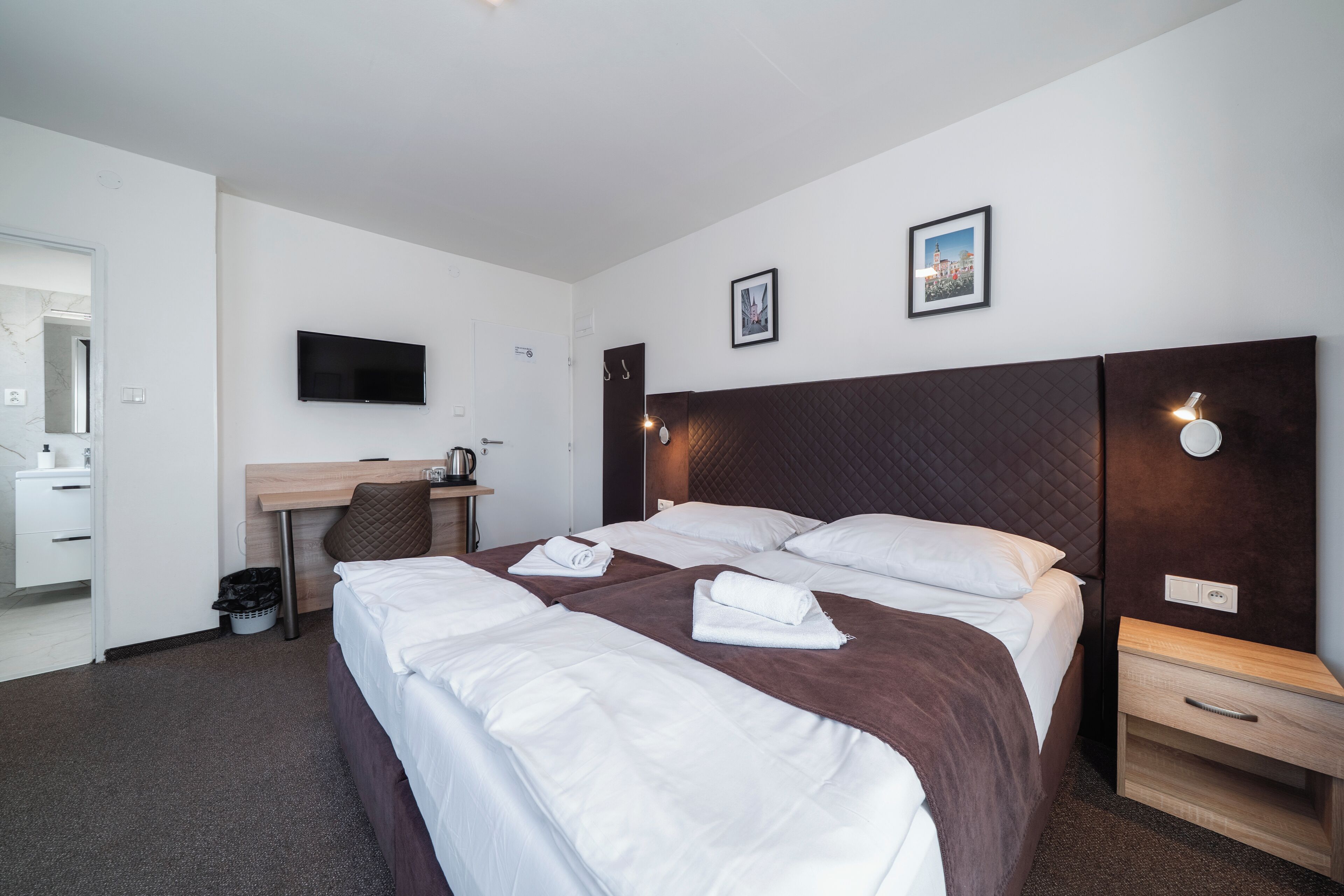 Een hotelkamer met een bed, een bureau, een televisietoestel en een schilderij aan de muur.