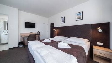 Een hotelkamer met een bed, een bureau, een televisietoestel en een schilderij aan de muur.