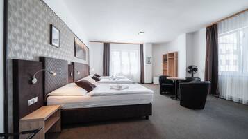Quarto de hotel moderno com uma cama grande, mesas de cabeceira, escrivaninha e uma cadeira.