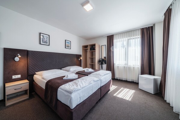 A hotel room with a large bed, bedside tables, a wardrobe, a desk, and a mirror.