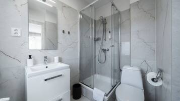 A modern bathroom with a glass-enclosed shower, a white sink, and a toilet.