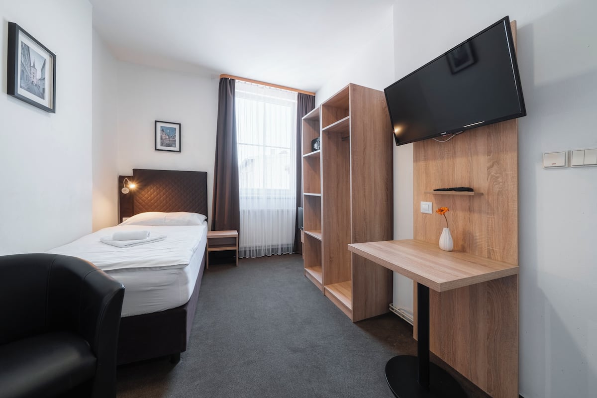 A hotel room with a bed, a desk, a TV, a wardrobe, and a chair.