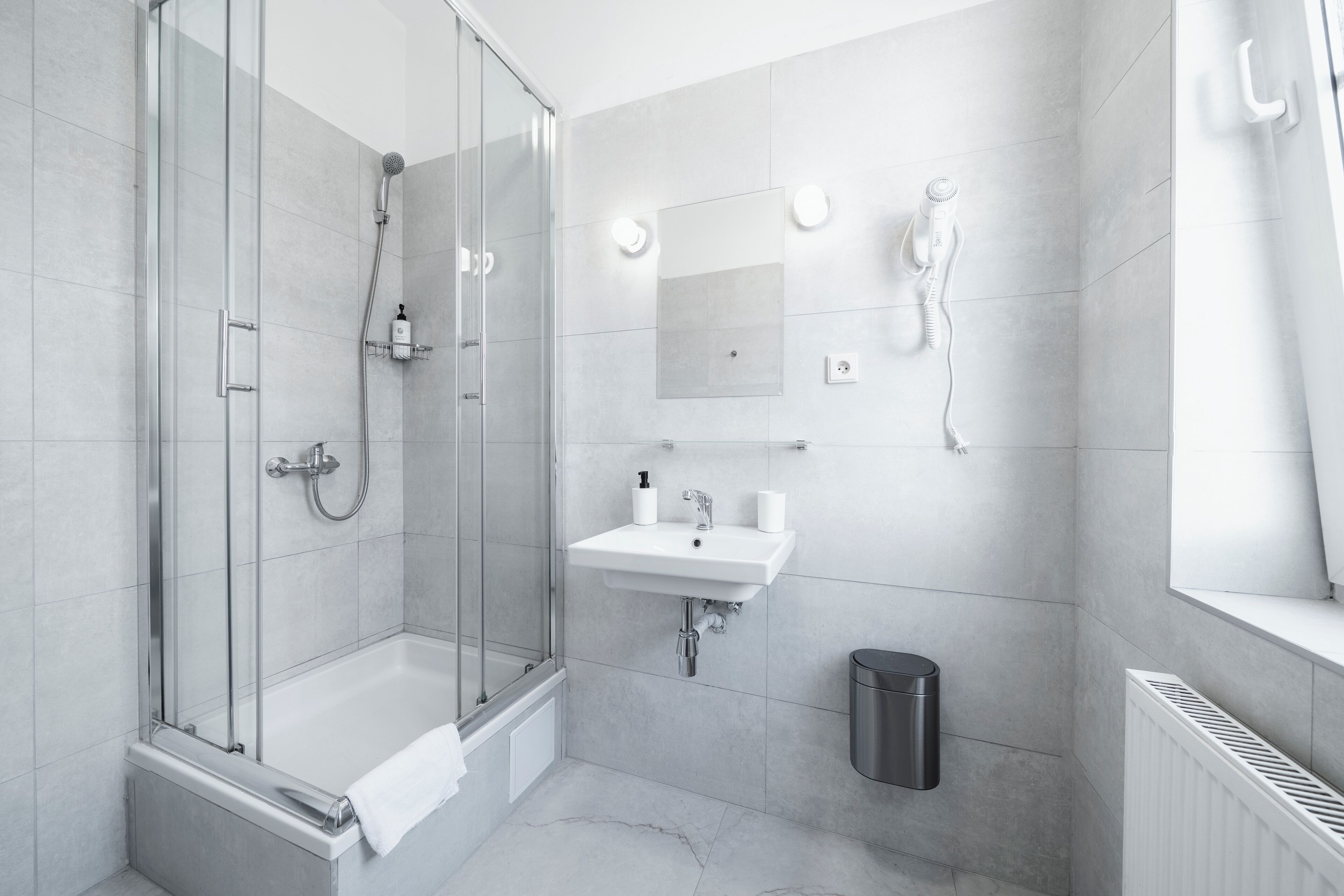 A modern bathroom with a glass-enclosed shower, a white sink, and a mirror.