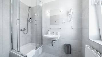 A modern bathroom with a glass-enclosed shower, a white sink, and a mirror.