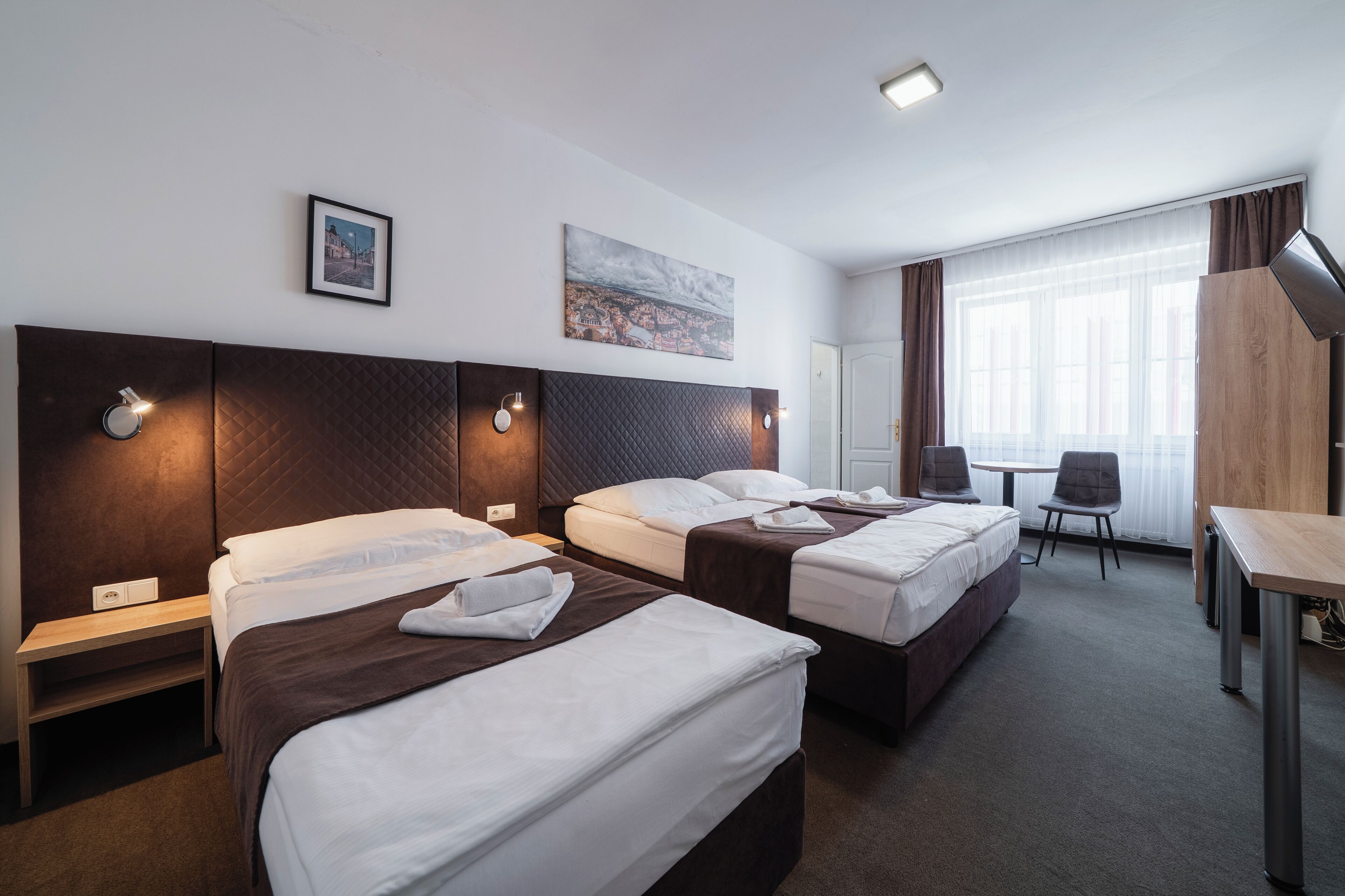 Ein Hotelzimmer mit zwei Betten, einem Schreibtisch und einem Sessel.