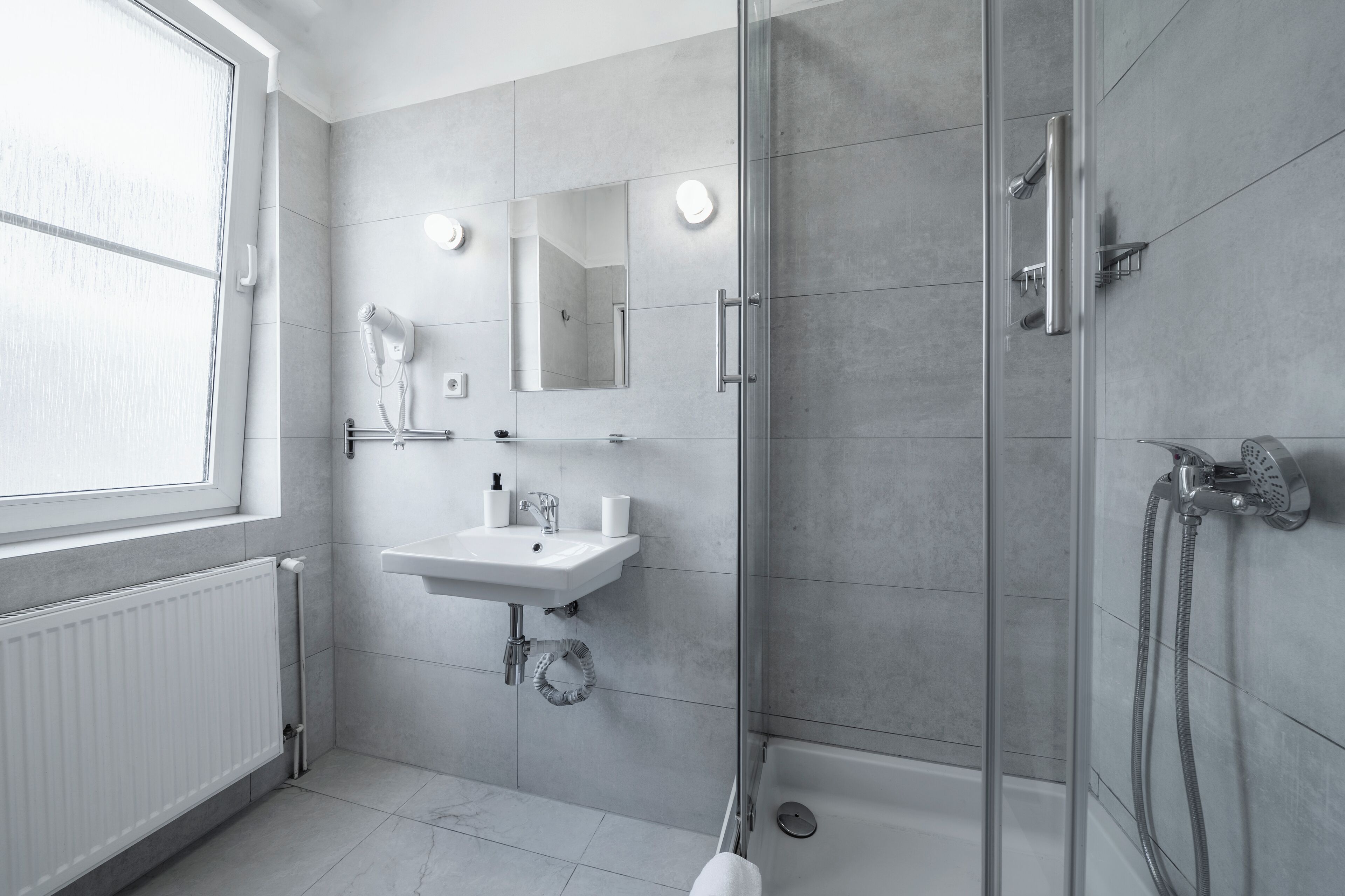 A modern bathroom with a glass shower enclosure, a white sink, and a mirror.