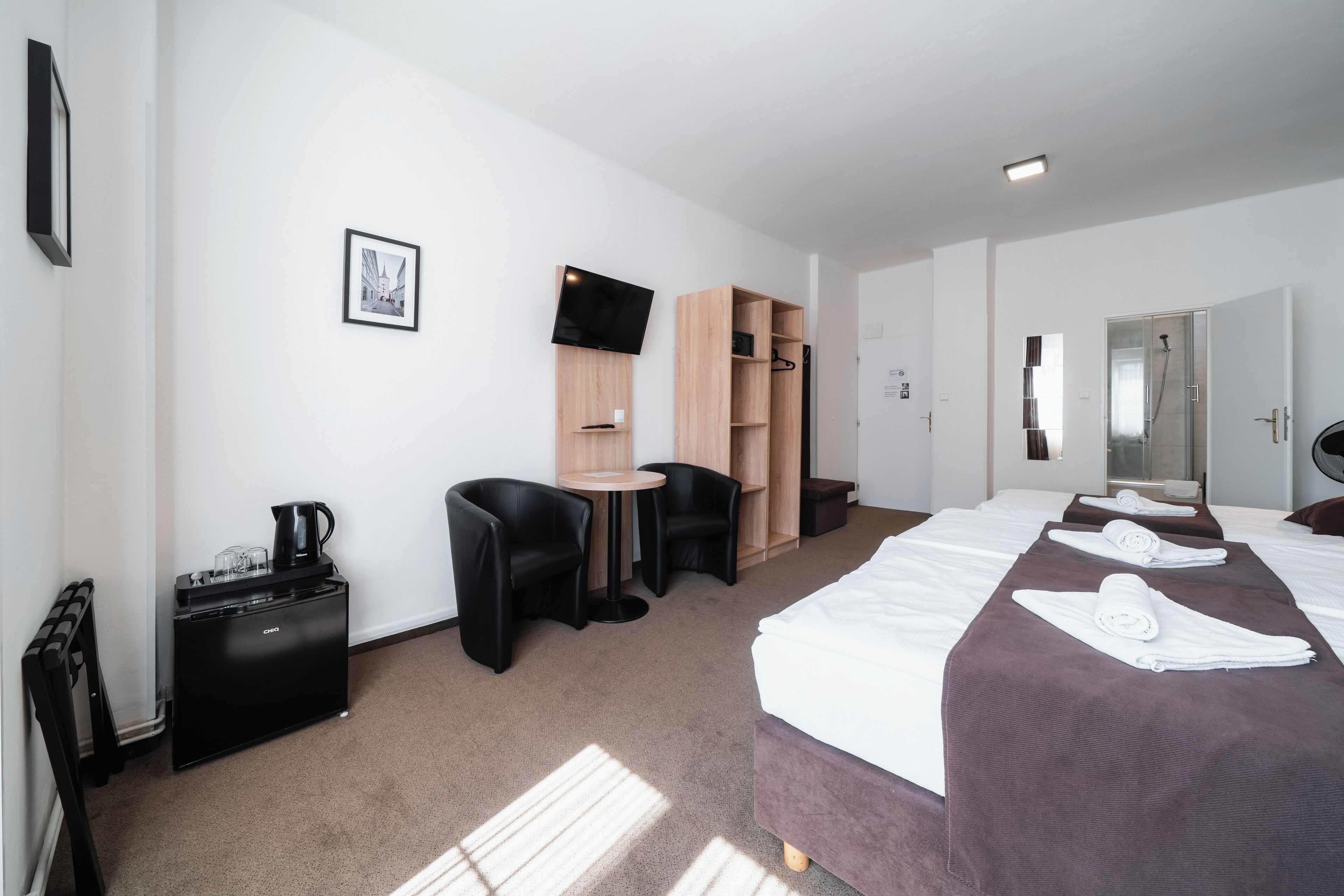 A hotel room with a bed, a desk, a coffee maker, a TV, and a wardrobe.