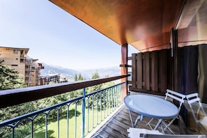 Enjoy breathtaking views of the surrounding mountains from this balcony with a table and two chairs.
