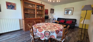 Un coin repas comprenant une table ronde, des chaises, un buffet contenant de la verrerie, un canapé et une lampe.