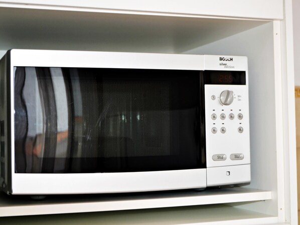 Un horno microondas blanco Bosch con pantalla digital, botones de control y un temporizador.
