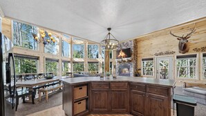 Une cuisine spacieuse avec une cheminée en pierre, des armoires en bois et de grandes fenêtres.