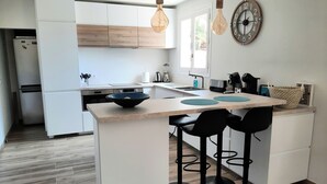 A modern kitchen with white cabinets, a central island with stools, and hanging light fixtures. - Casa Verde, cozy holiday home with private heated pool in Javea (Jávea)