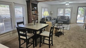 A living room with a dining table, chairs, a sofa, and a lamp. - Dogs Give us 5 Stars! 3BR, Large Fenced Yard, Rustic Escape (Orange Park)
