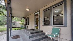 A covered porch with steps leading to a door, a green chair, and a small table. - Dogs Give us 5 Stars! 3BR, Large Fenced Yard, Rustic Escape (Orange Park)