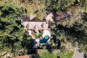 Eine Vogelperspektive eines Wohnhauses mit Swimmingpool, einer freistehenden Garage und einem großen Garten.
