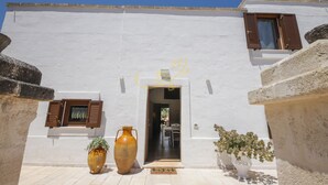 A white building with a door, two windows with shutters, and a potted plant. - TD Villa Ricchiari  | Design Villa with Heated Pool (Fasano)