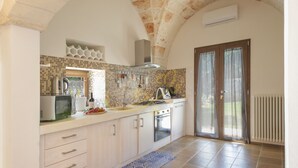 A kitchen with a tiled backsplash, a microwave, a stove, and a sink. - TD Villa Ricchiari  | Design Villa with Heated Pool (Fasano)