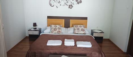 A neatly arranged hotel room with a large bed, two nightstands, a bedside table, and a decorative wall piece.