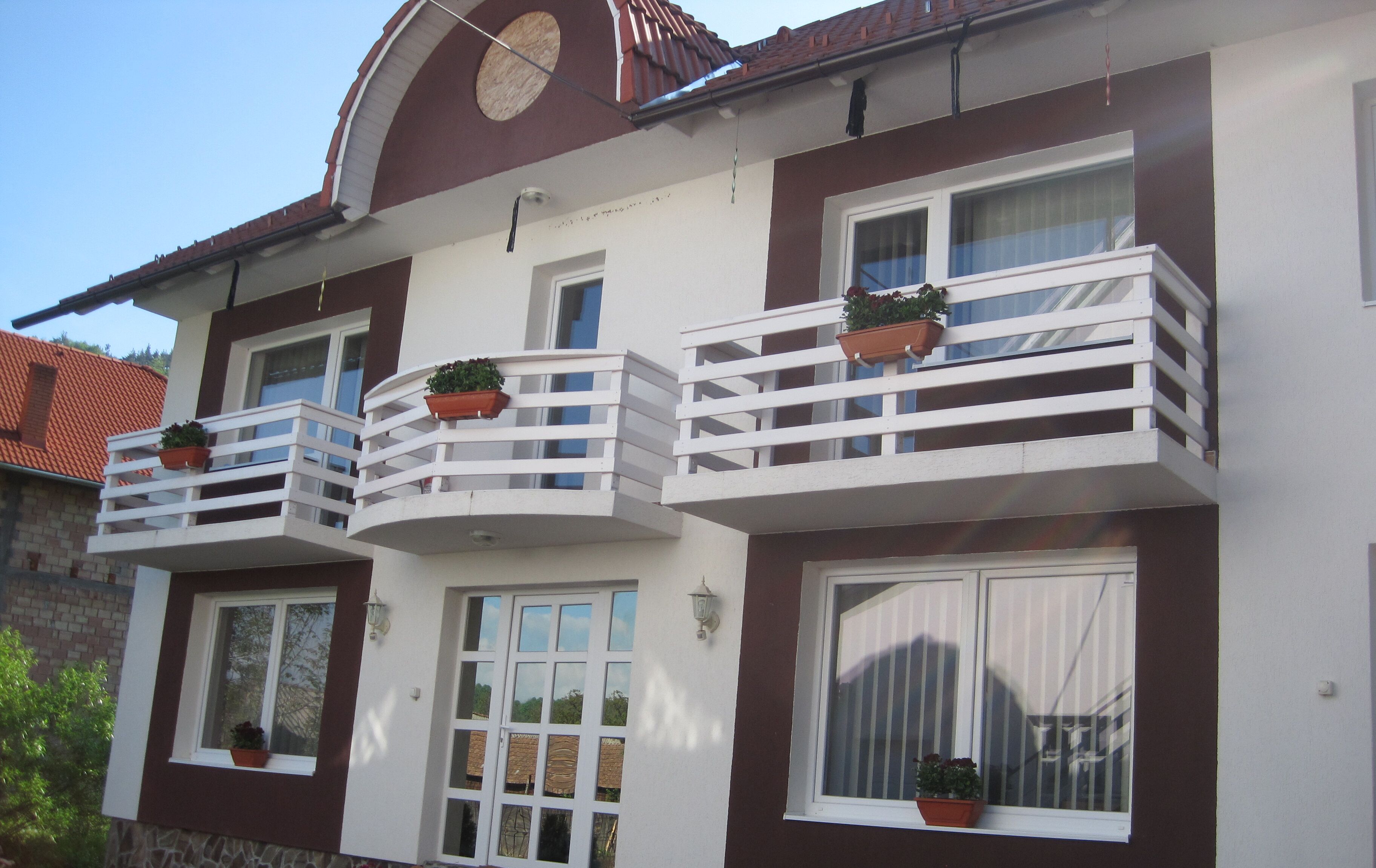 A multi-story building with balconies, each with a potted plant.