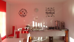 A kitchen with a red and white color scheme, a coffee machine, and two wall decorations with motivational sayings.