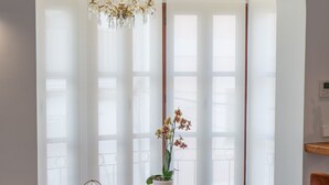Un espace repas avec une table en bois, des sièges rembourrés de couleur rouge, une orchidée en pot et un lustre.