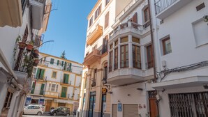 Une rue étroite bordée de bâtiments des deux c ôtés, avec des balcons et un mélange de styles architecturaux.