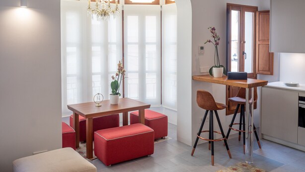 Une cuisine moderne avec un coin repas, comprenant une table en bois, des chaises rouges et un lustre.