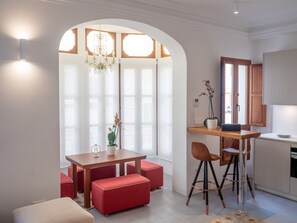 Una cocina moderna con comedor, que incluye una mesa de madera, sillas rojas y una araña.