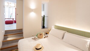 Une chambre à coucher comprenant un lit, une table de chevet, un miroir et un escalier menant à une autre pièce.